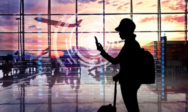 Airport terminal at sunset with passengers looking smartphone.
