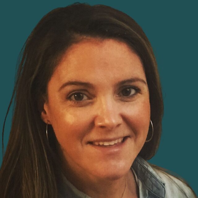 A smiling woman with shoulder-length brown hair and hoop earrings poses for a professional headshot against a teal background.